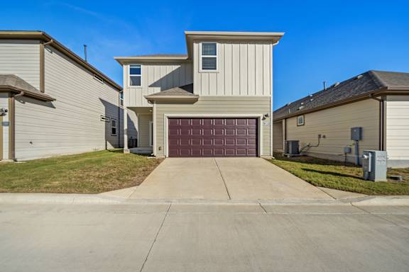 A two-story house with a garage door in the middle.