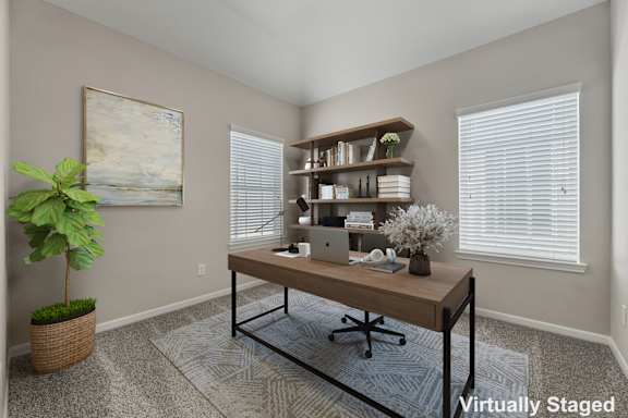 A room with a desk, chair, and a painting on the wall.