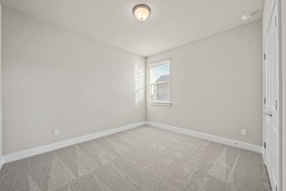A room with a carpeted floor and a window with blinds.