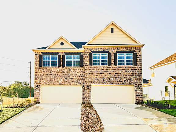 A two-car garage is attached to a brick house.