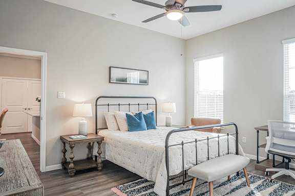 A bedroom with a bed, chair, and a ceiling fan.