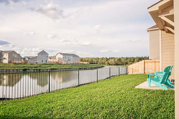 A green lawn chair sits on a concrete slab in a yard.