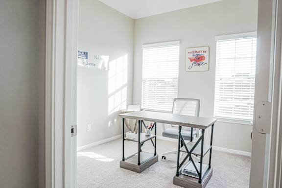 A room with a desk and a sign that says "This Must Be The Place".