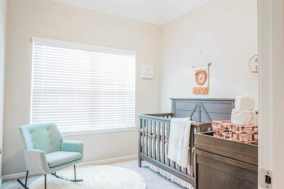 A baby nursery with a blue chair and a crib.