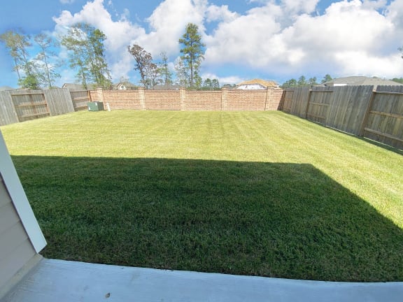 a backyard with a grassy area and a brick fence