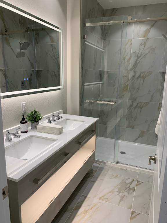 A bathroom with a glass shower and marble walls.
