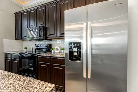 A kitchen with a stainless steel refrigerator and black cabinets.