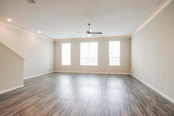 A spacious room with wooden flooring and a ceiling fan.