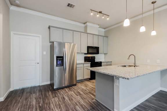 A modern kitchen with a stainless steel refrigerator and a granite countertop.