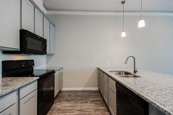 A kitchen with black appliances and granite countertops.