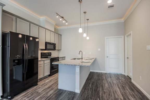 A kitchen with a black refrigerator, white cabinets, and a white island.