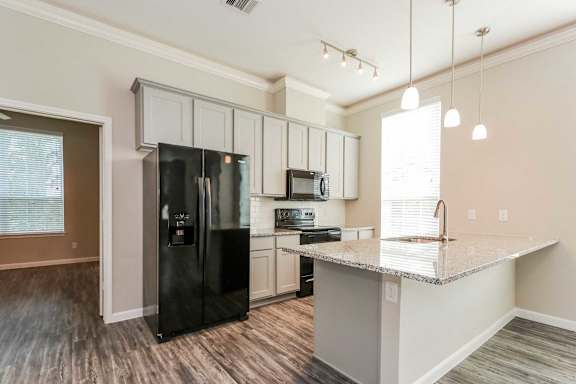 A kitchen with a black refrigerator and white cabinets.