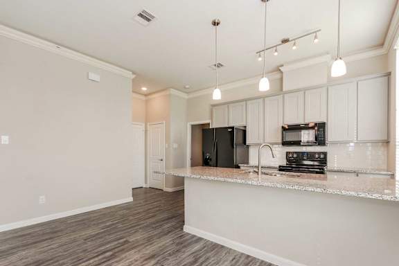 A kitchen with a black microwave and oven built into the countertop.