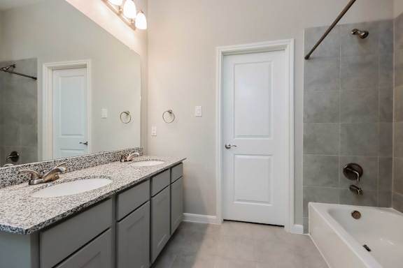 A bathroom with a sink, mirror, and bathtub.