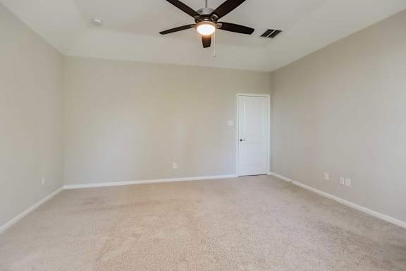 A room with a ceiling fan and carpeted floor.