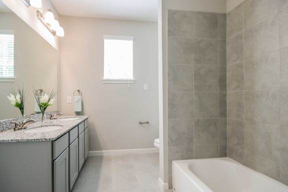 A bathroom with a tub, sink, and a window.