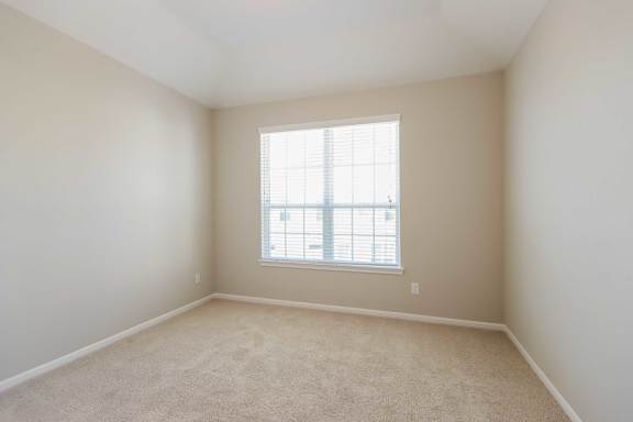 A room with a window and carpeted floor.