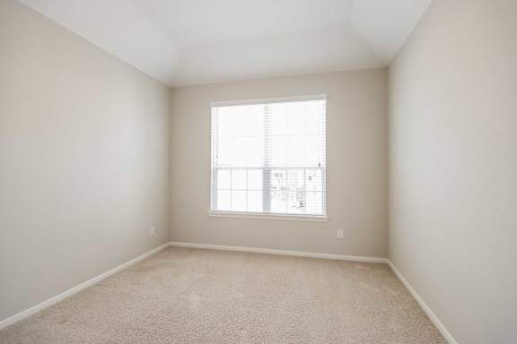 A room with a window and carpeted floor.