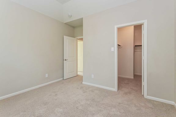A room with a carpeted floor and two doors.