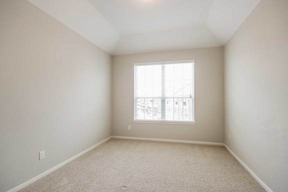 A room with a window and carpeted floor.