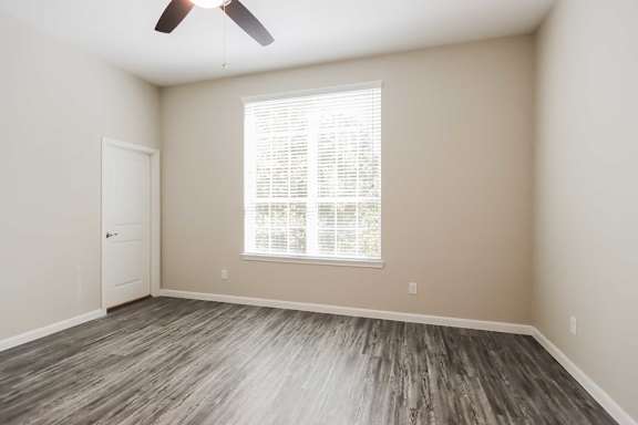 A room with a ceiling fan and a window with blinds.