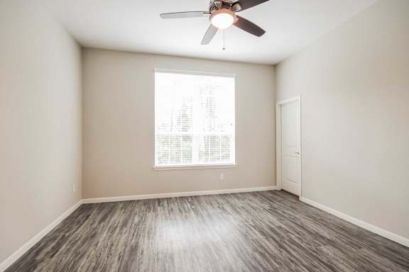 A room with a ceiling fan and a window with blinds.