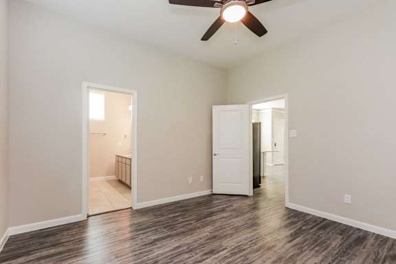 A room with a ceiling fan and wooden flooring.
