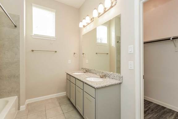 A bathroom with a sink, mirror, and lighting fixture.