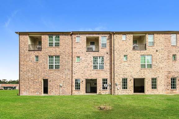 A large brick building with a green lawn in front.