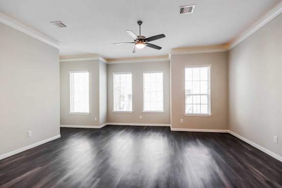 A room with a ceiling fan and wooden floors.