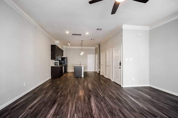 A room with a dark wood floor and a ceiling fan.
