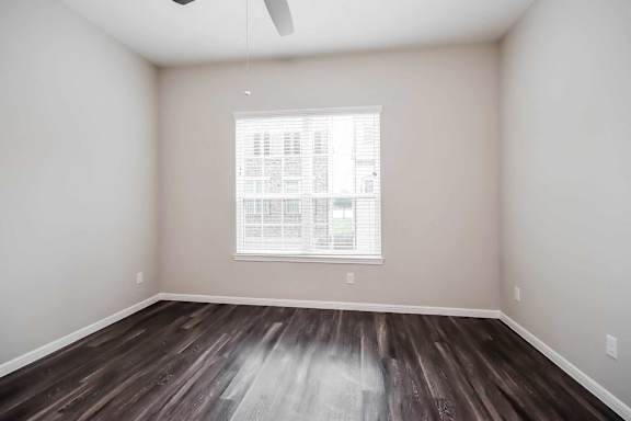 A room with a window and wooden flooring.