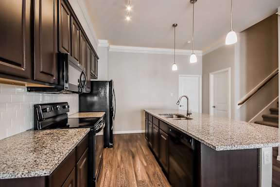 A kitchen with dark brown cabinets and a granite countertop.