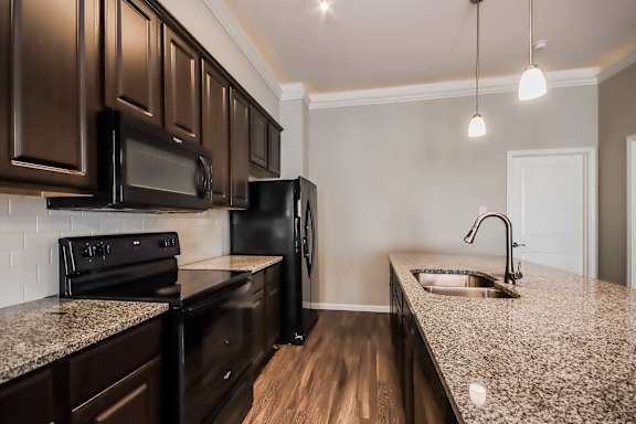 A kitchen with dark brown cabinets and black appliances.