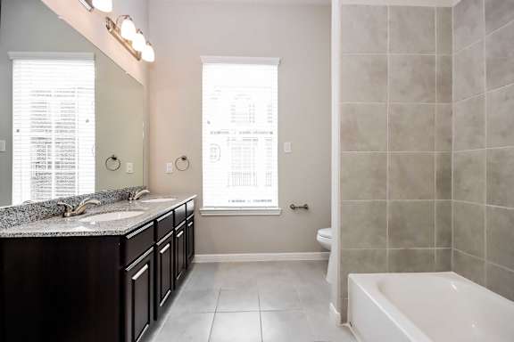 A bathroom with a tub, sink, and mirror.
