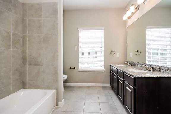 A bathroom with a white tub and black countertops.