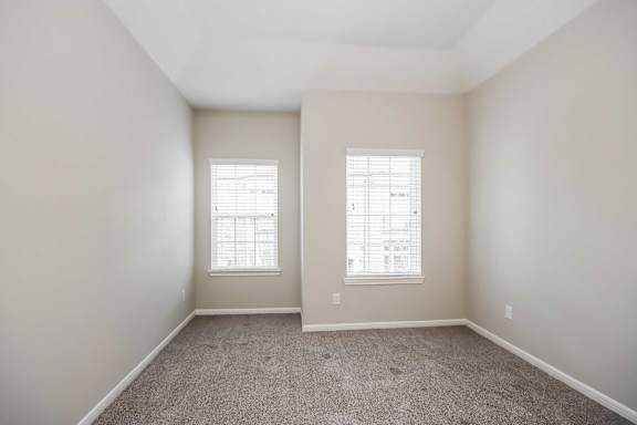 A room with two windows and carpeted floor.
