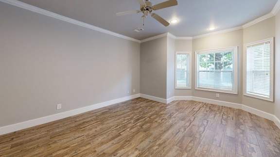 A room with a ceiling fan and hardwood flooring.