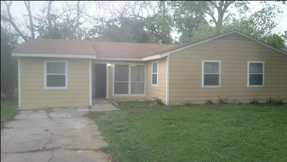 A small house with a brown roof and tan siding.