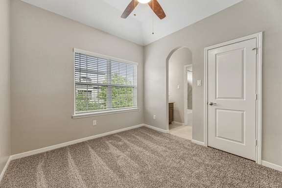 A room with a ceiling fan and a window with blinds.
