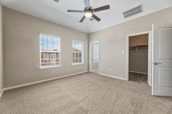 A room with a ceiling fan and carpeted floor.
