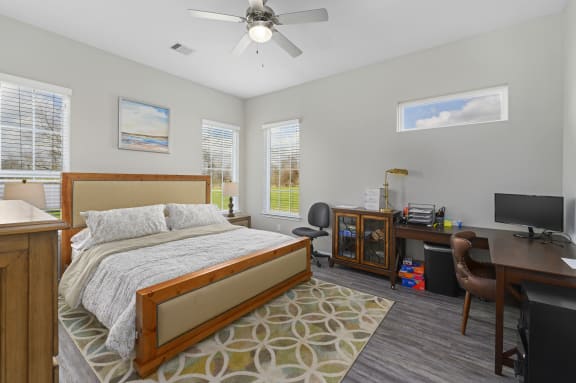 a bedroom with a bed and a desk and a ceiling fan