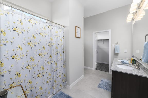 a bathroom with a shower curtain with yellow flowers on it