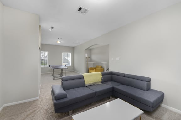 a living room with a gray couch and a white table