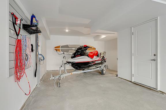 A boat is parked in a garage next to a wall with hooks.