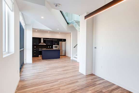 a renovated living room and kitchen with wood floors and white walls