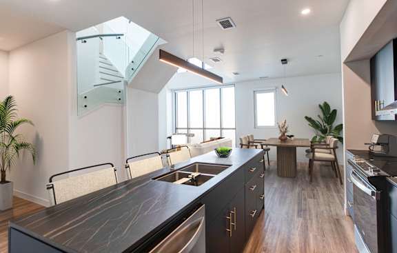 a kitchen with a sink and a dining room with a table and chairs