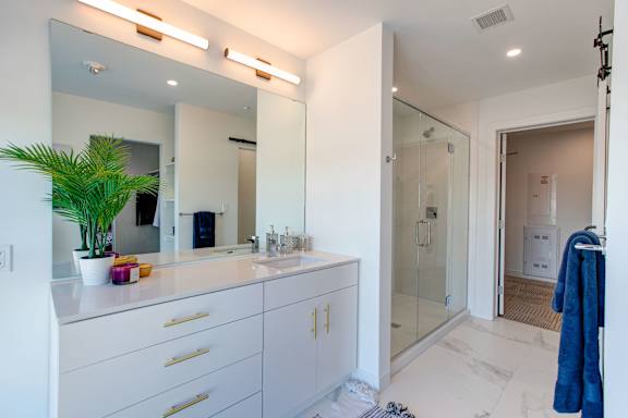 a white bathroom with a large mirror and a sink and a shower