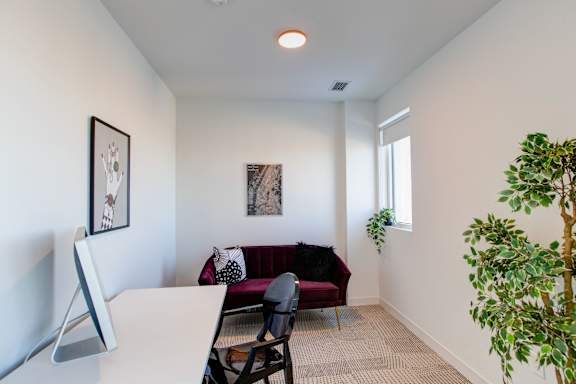 a living room with a couch and a desk and a window