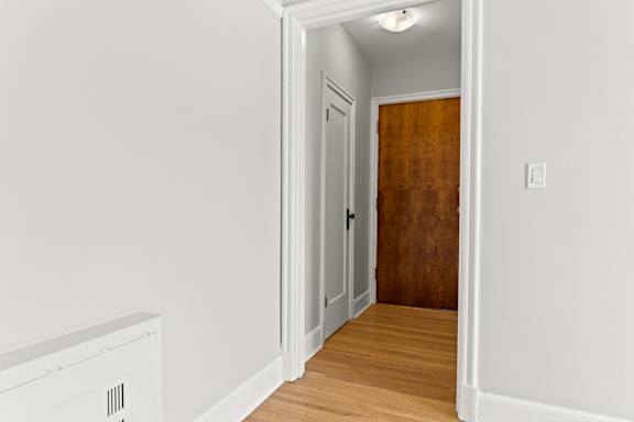 A room with a white wall and a brown door.